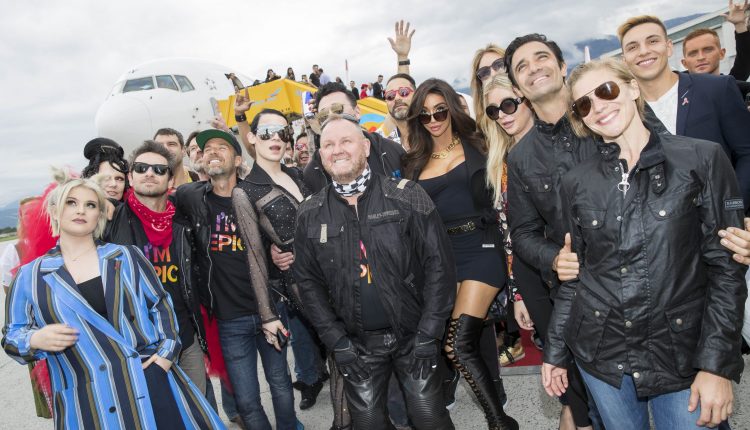 Eine Gruppe von Menschen, die an einem bewölkten Tag vor einem Flugzeug posieren und lächeln.