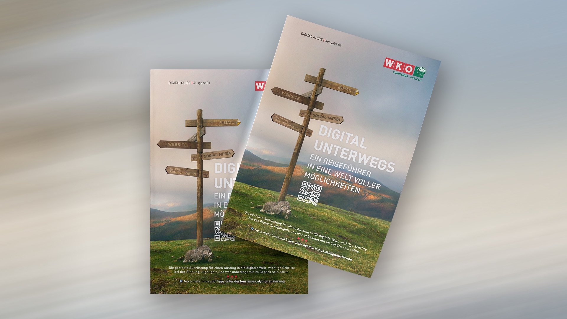 Zwei Broschüren mit einem Wegweiser auf einem grasbewachsenen Hügel, beschriftet mit "Digitaler Unterwegs" und einem QR-Code am unteren Ende.