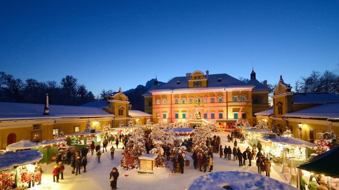 Ein festlicher Weihnachtsmarkt bei Nacht mit bunten Lichtern, geschmückten Ständen und Menschen, die im Schnee spazieren gehen.