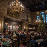 Essen für große Gruppen in einem großen Saal mit Kronleuchtern und einem geschmückten Weihnachtsbaum.