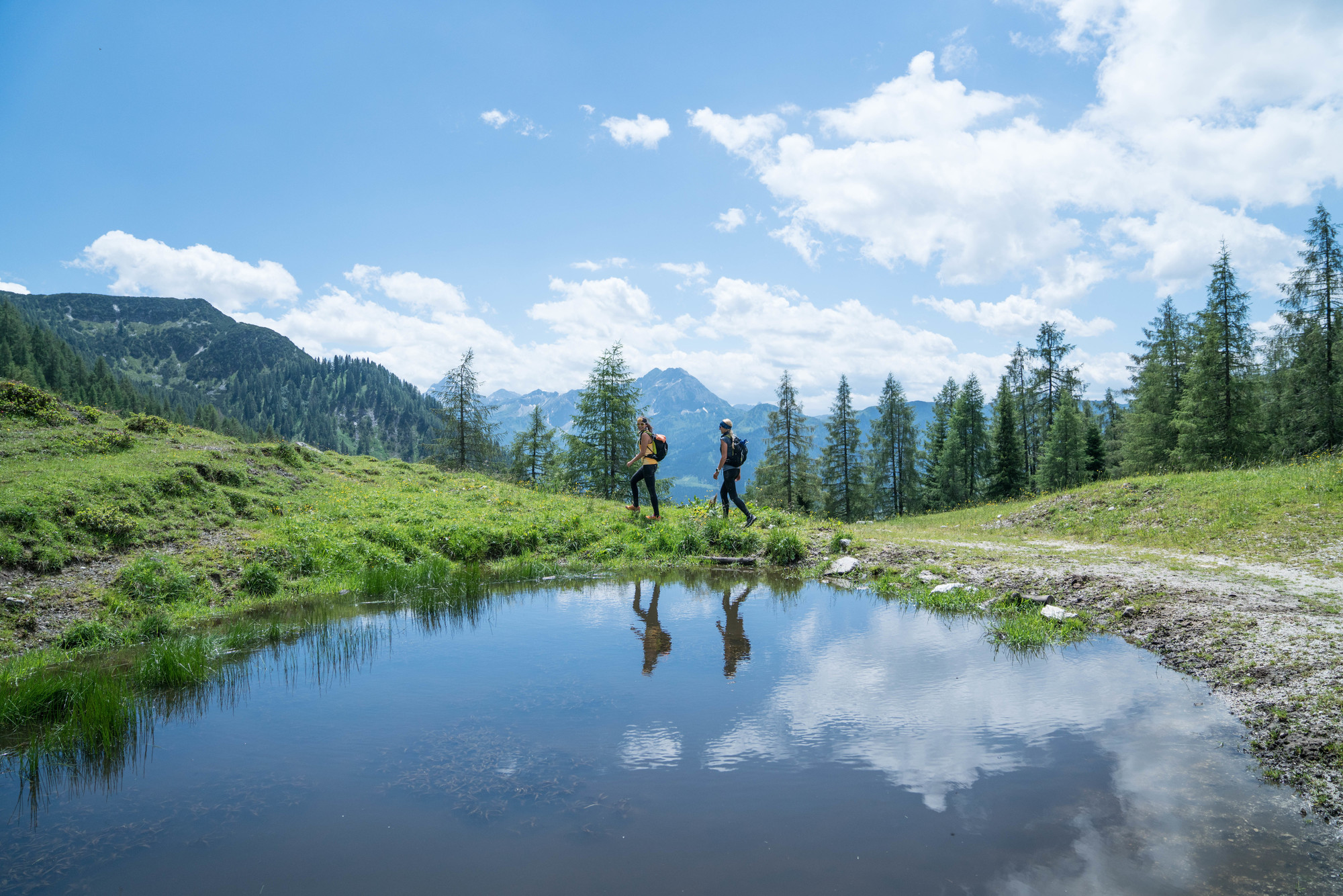 zwei Frauen (beide um die 30 Jahre alt) spiegeln sich in den Lacken des Lackenkogels.
