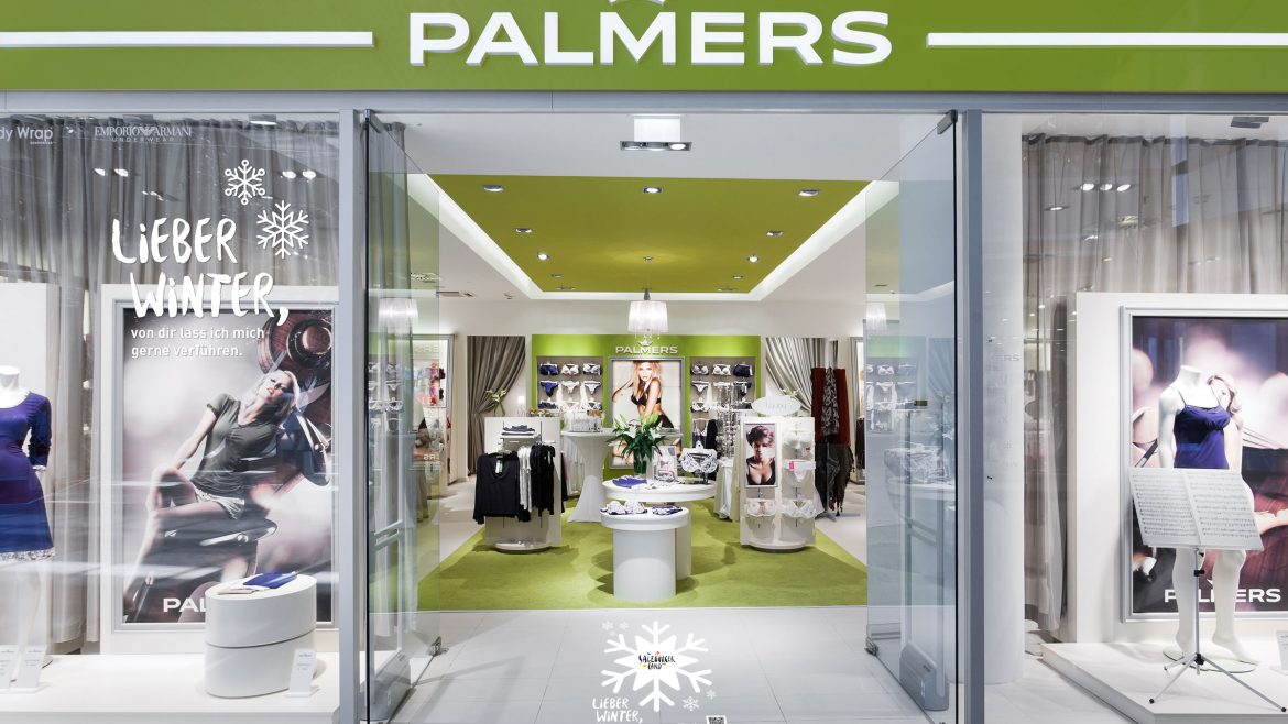 Schaufenster von Palmers mit grünem Schild, Schaufensterpuppen in Unterwäsche und moderner, gut beleuchteter Innenauslage.