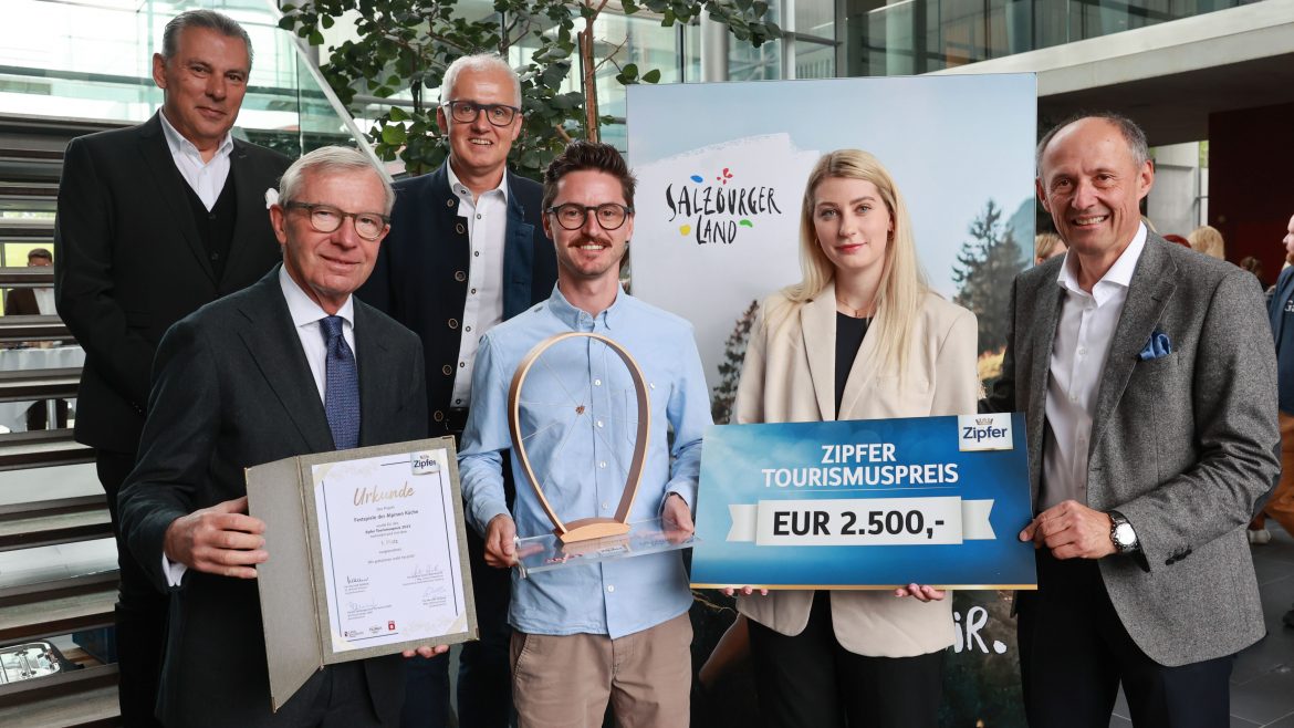 Sechs lächelnde Menschen in einem Raum, die eine Auszeichnung, eine Urkunde und ein Schild mit einem Tourismuspreis von 2 500 € in der Hand halten.