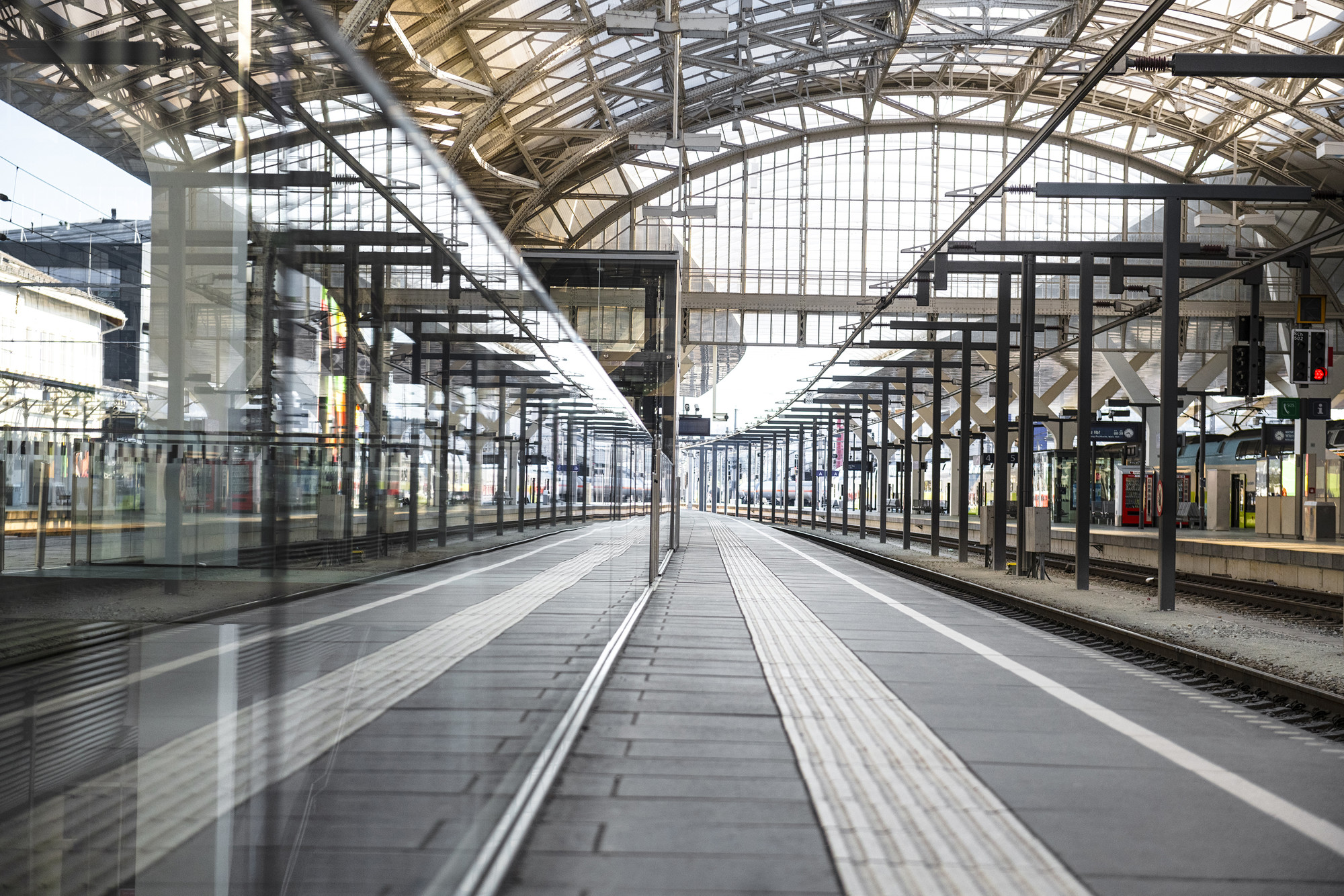 Leeres Bahnhofsgebäude mit Glasdach und Spiegelungen, das mehrere Gleise und Bahnsteige zeigt.