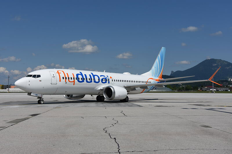 Ein Flugzeug der Fluggesellschaft Flydubai auf dem Rollfeld, im Hintergrund Berge und blauer Himmel.