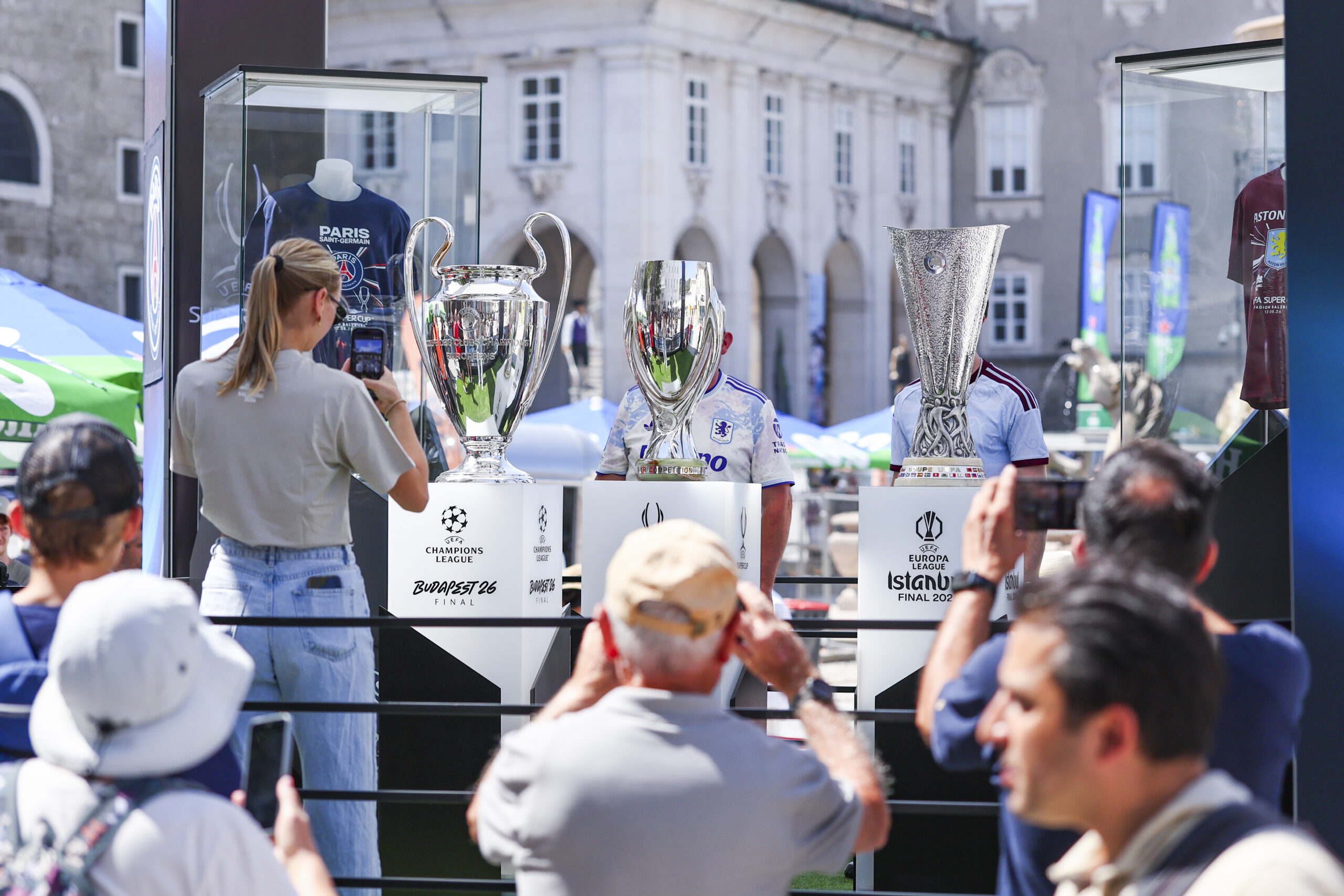 Besucher fotografieren drei große Fußballpokale