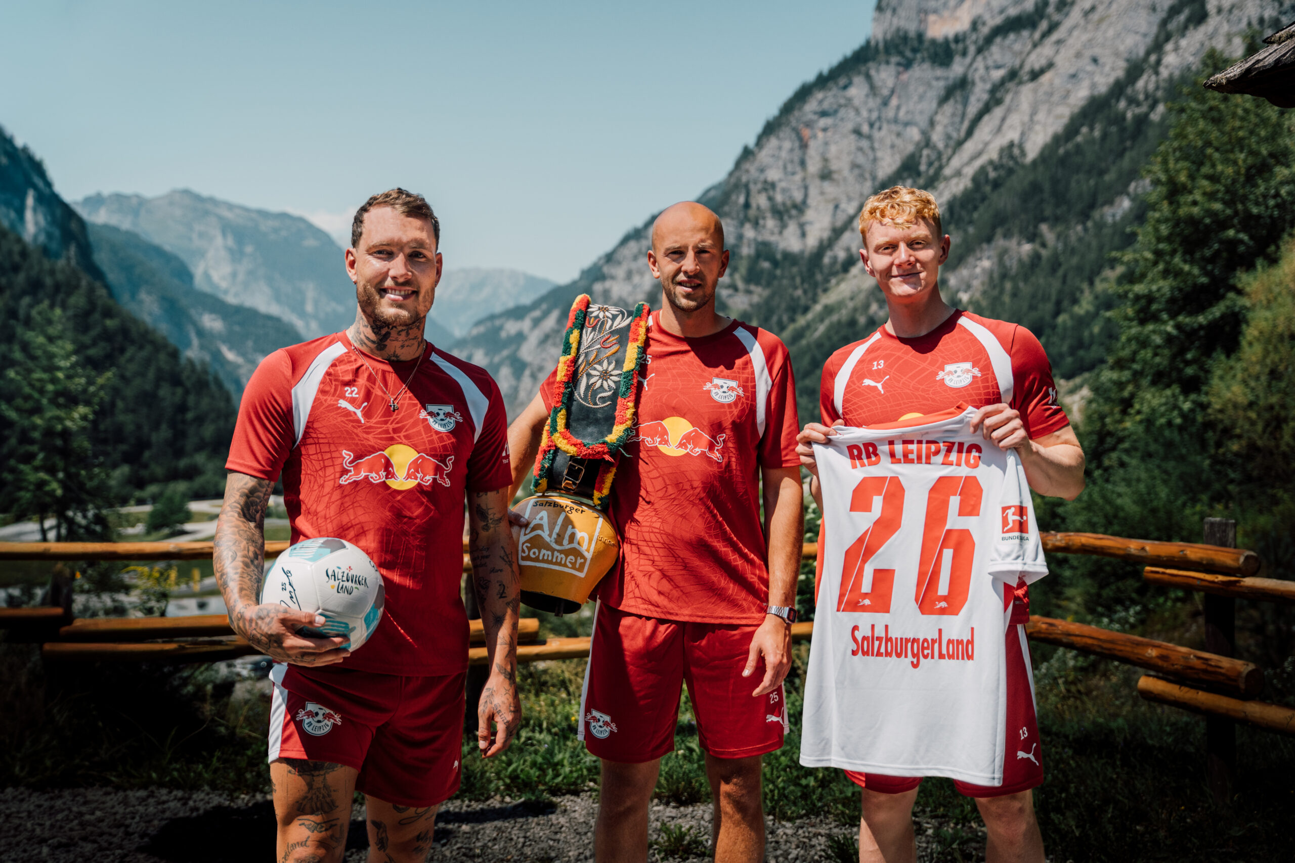 Drei Fußballspieler in roten Trikots des RB Leipzig posieren im Freien