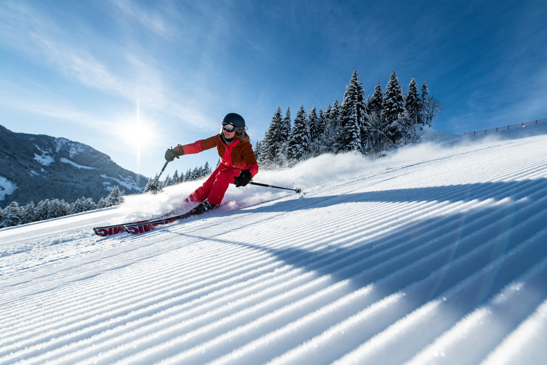 Ein Skifahrer, der auf einer präparierten Piste in den österreichischen Bergen eine Kurve zieht.