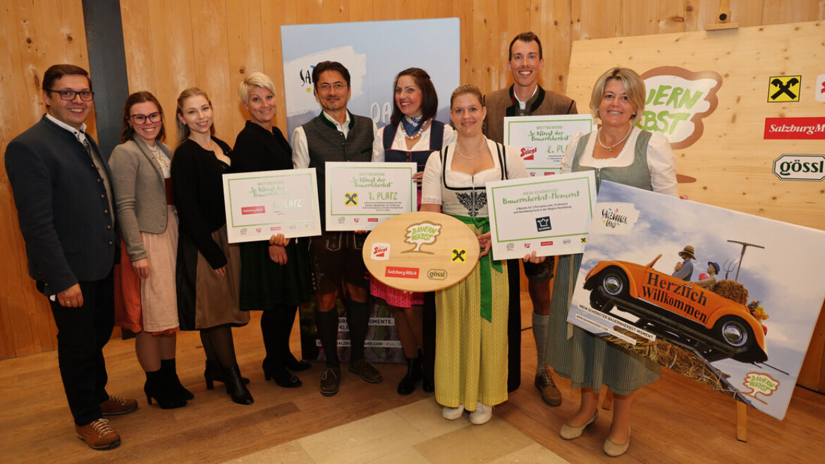 Eine Gruppe von Menschen in österreichischer Tracht, die mit Preisplakaten und einer Holz-Trophäe posieren.