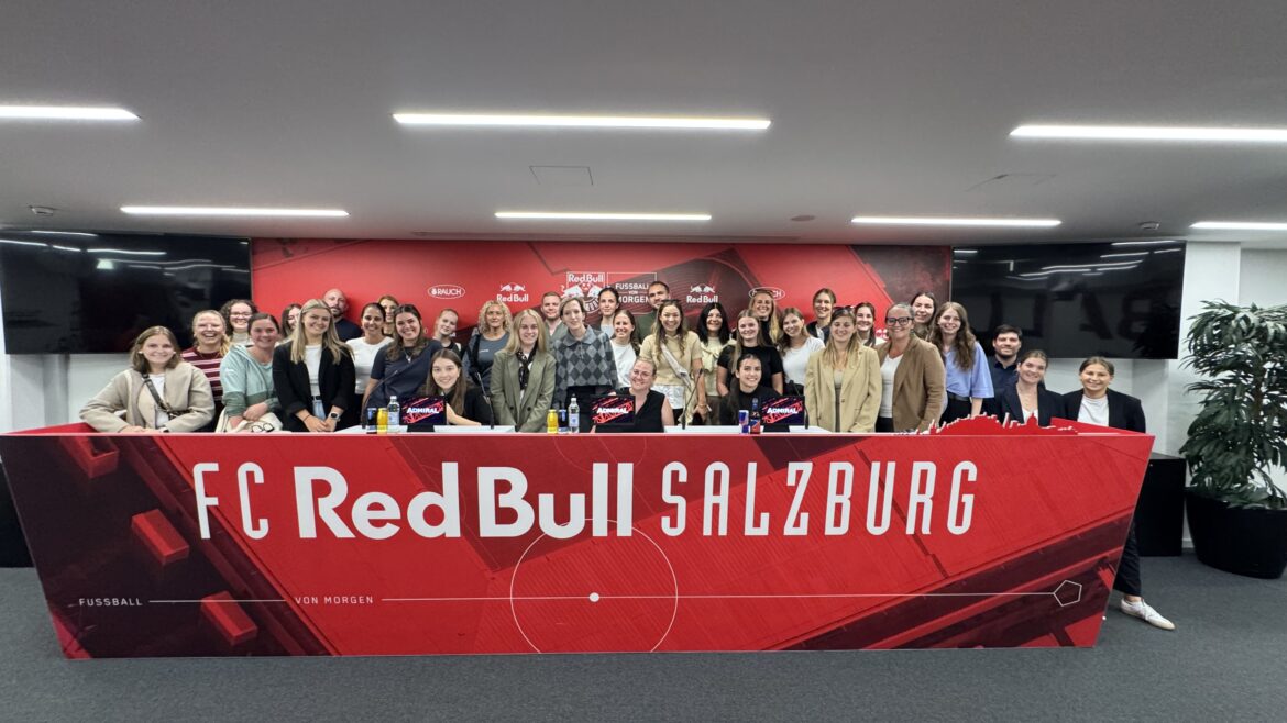 Eine große Gruppe von Menschen, die hinter einem roten Banner mit der Aufschrift FC Red Bull Salzburg für ein Foto posiert.